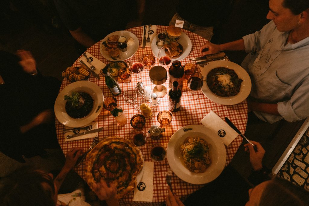 Uppdukat bord med rödrutig duk, pizza, pasta och rödvin en kväll på Joe Farelli’s